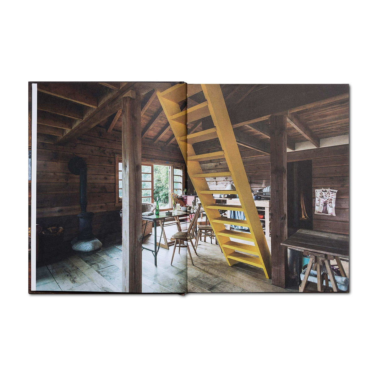 Interior of a rustic cabin from Cabin Porn Inside book featuring wooden furniture and a yellow staircase. Available at Cabin Depot.