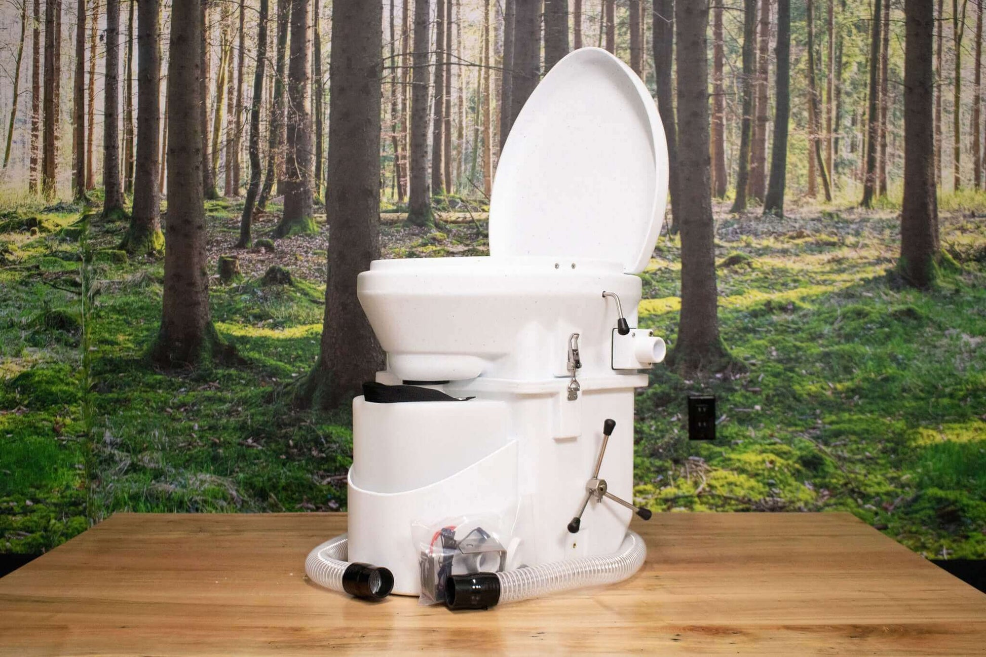 Nature's Head composting toilet with foot spider handle by Cabin Depot, displayed on wooden surface with forest background.