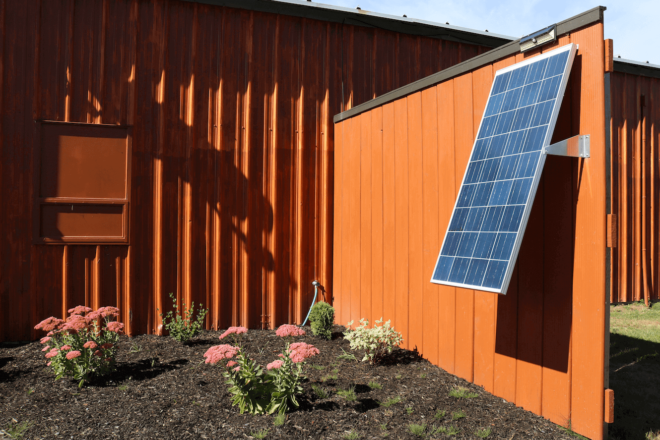 Solar panel mounted with Kedron L Bracket on barn wall, ideal for solar installations, Cabin Depot solar accessories, secure mounting solution.