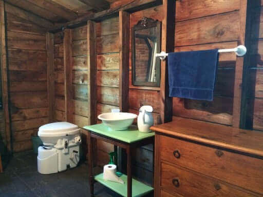Nature's Head composting toilet with foot spider handle in rustic cabin bathroom by Cabin Depot.